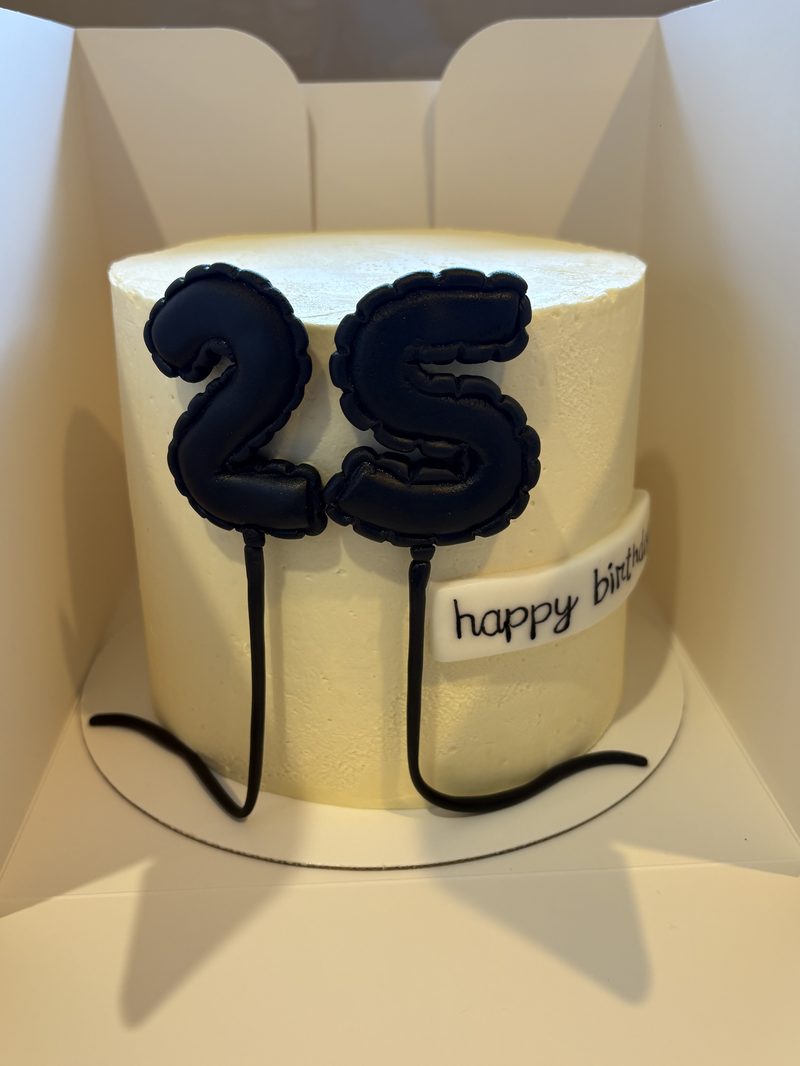 A tall celebration cake with piped buttercream and a gold 25 birthday topper